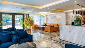 A modern lobby with a reception desk, blue sofas, and a marble floor. - The King Hotel condotel Thai Nguyen (Phan Dinh Phung)