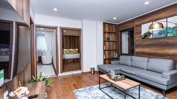 A modern living room with a grey sectional sofa, wooden flooring, a coffee table, and a painting on the wall.