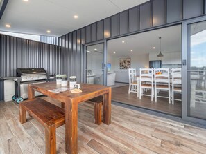 Una cucina moderna con una griglia integrata, un'area pranzo con tavolo e sedie in legno, e un'ampia porta-vetrina scorrevole che dà su un balcone.