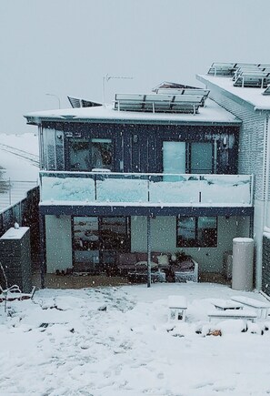 Un edificio di due piani con un balcone e pannelli solari sul tetto.
