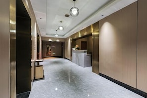 A hotel lobby with a reception desk, a reception area, and a door leading to another room. - Kailai Wisdom Hotel (Chongqing)