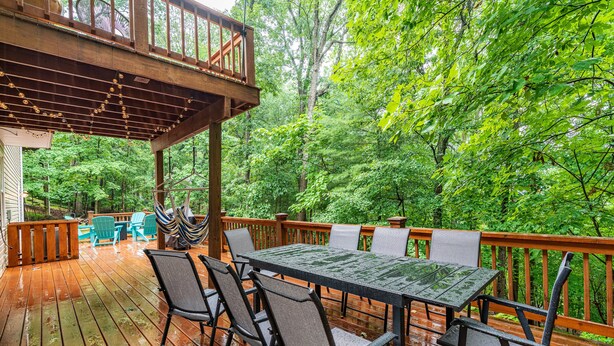 Une terrasse en bois avec une table et des chaises, entourée d’une végétation luxuriante.