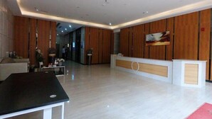 Eine geräumige Lobby mit einer Rezeption, einem schwarzen Tisch und einer Holzwand.