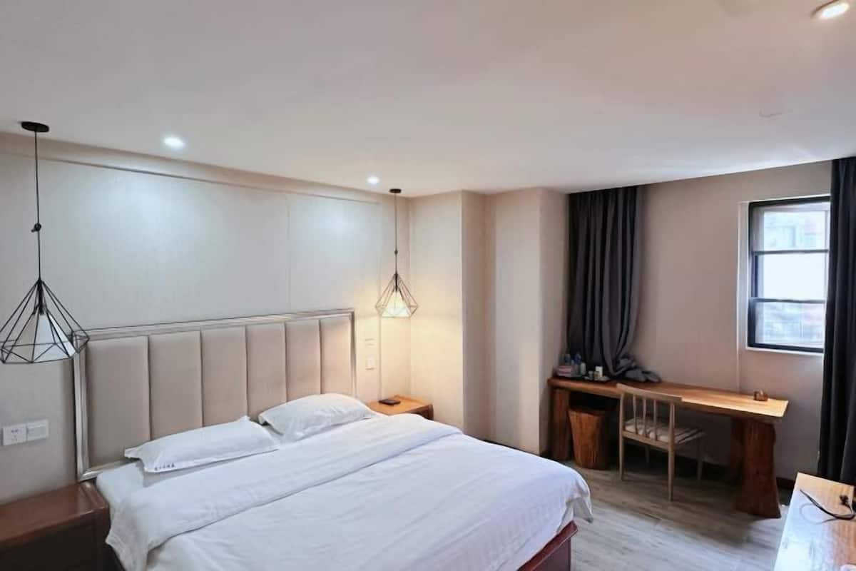 A bedroom with a bed, bedside tables, a desk, and a window with curtains.