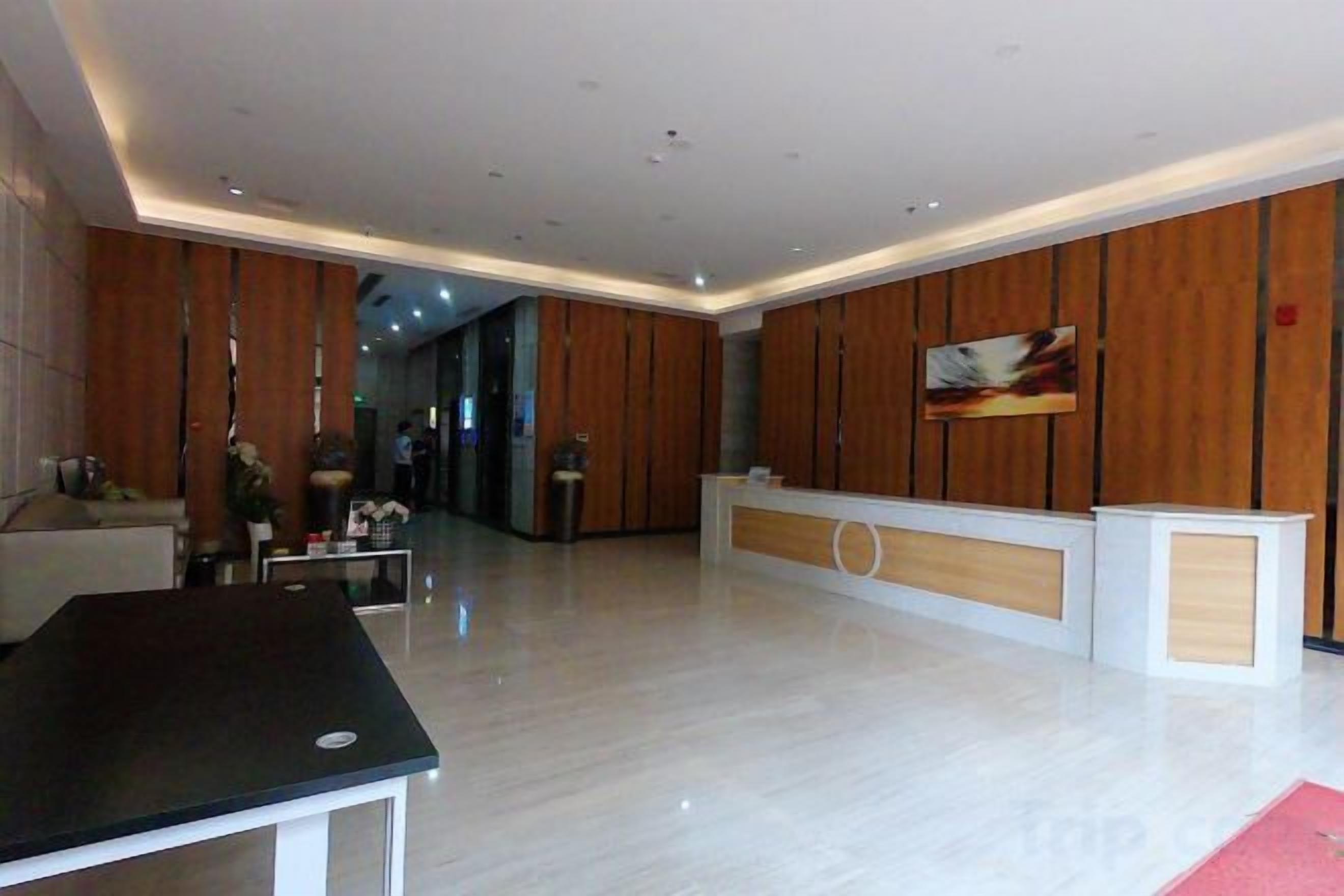 Un vestíbulo de hotel con un mostrador de recepción, una sala de espera y una zona de recepción.