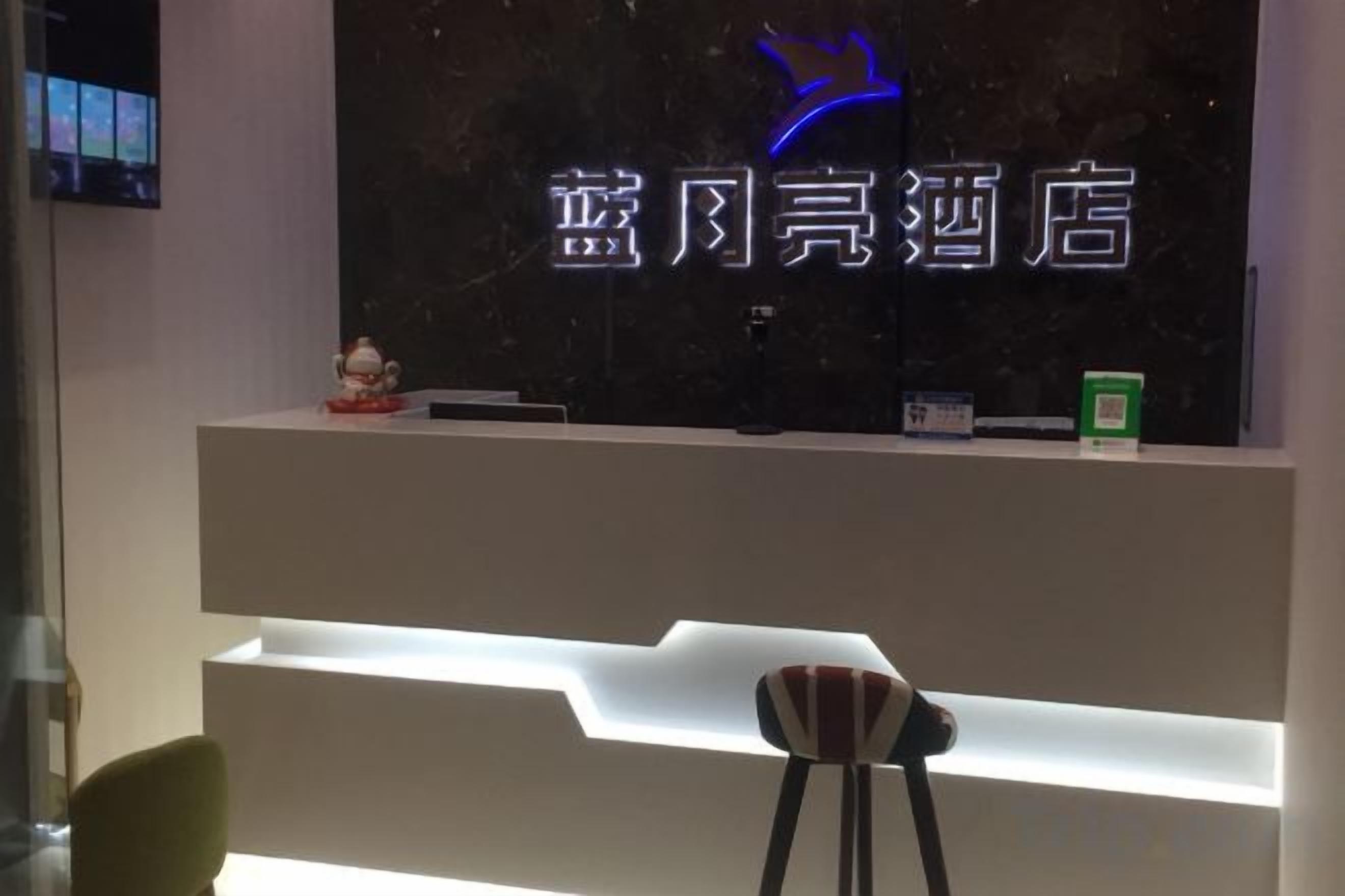 A reception desk with a neon sign, a small statue, and a green box on the counter.