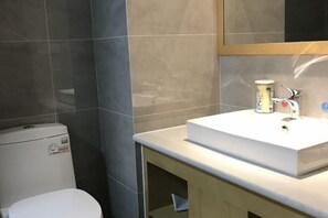A bathroom with a white toilet, a white sink, and a mirror above the sink. - Blue Moon Hotel (Kunming)