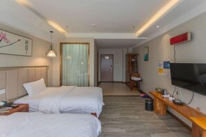 Habitación de hotel con dos camas, televisión, un banco de madera y un cuadro en la pared.