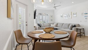A dining area with a round table, four chairs, a ceiling fan, and a light fixture with multiple bulbs. - FREE GOLF! Resort Style 1st floor condo in Great Location! Heated Pool/Spa/Gym, Near Shops/Dining! (Scottsdale)