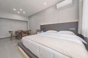 A modern hotel room with a large bed, a desk, and a chair.