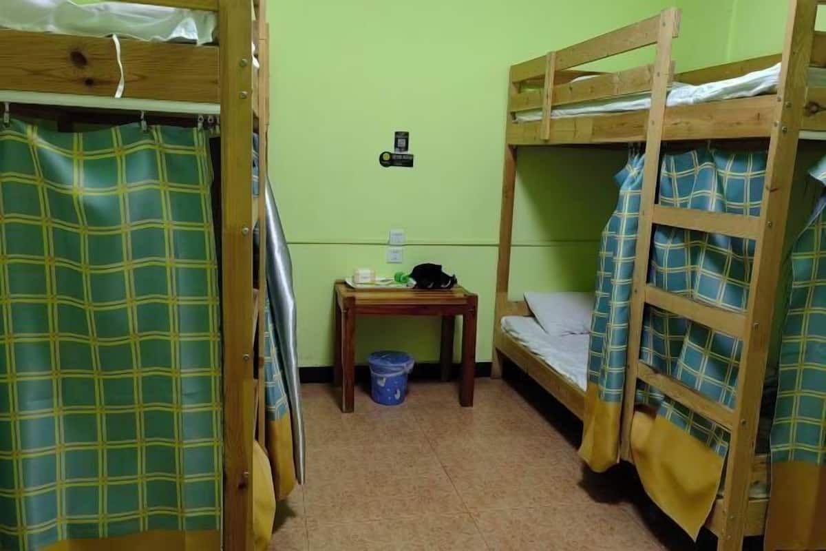 A small, compact room with bunk beds, a small table, and a trash bin.