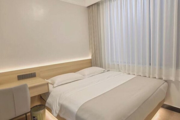 A modern hotel room with a bed, a desk, and a chair.