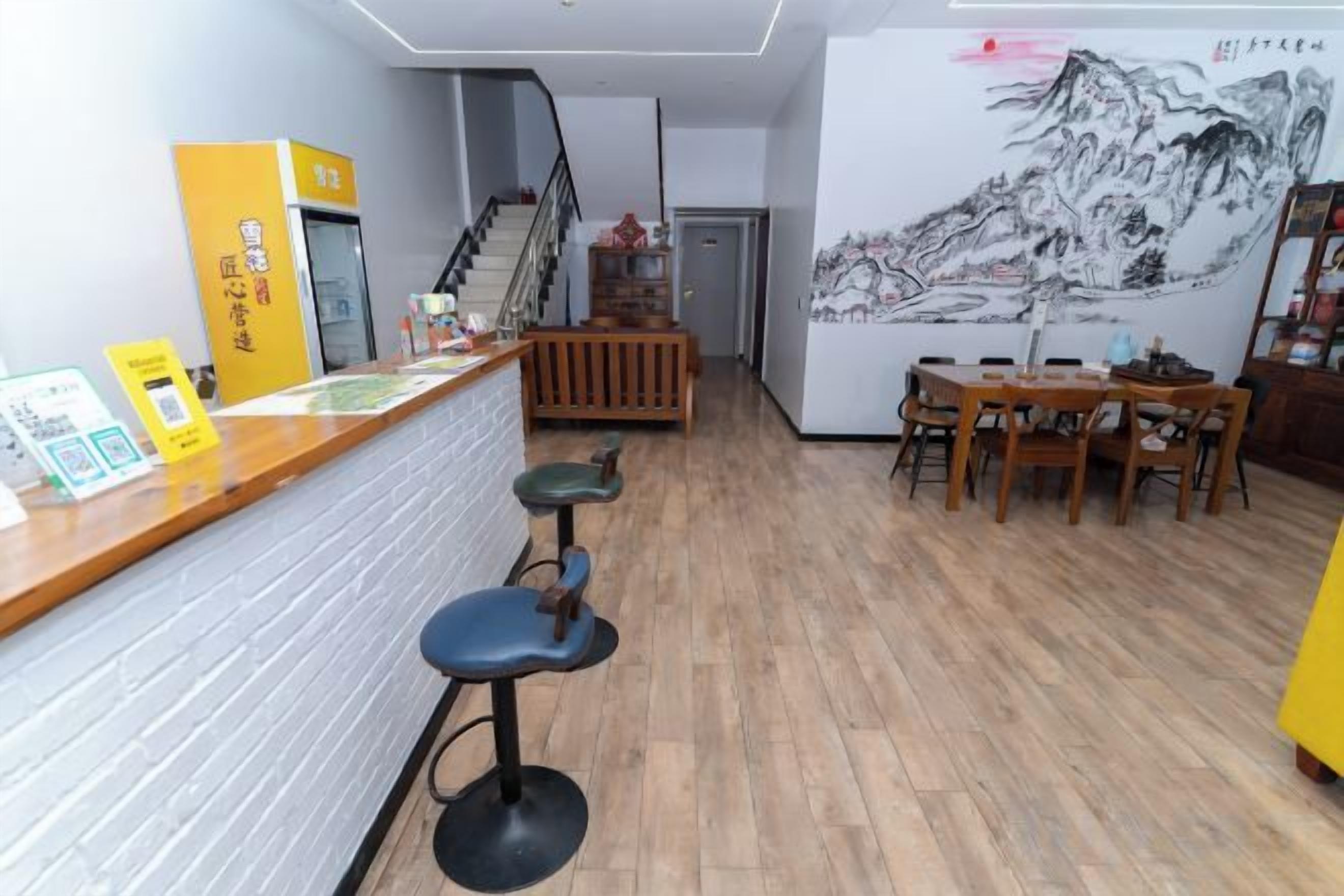 A restaurant interior with a bar area, stools, a staircase, and a mural on the wall.