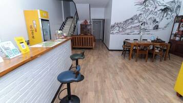 A restaurant interior with a bar area, stools, a staircase, and a mural on the wall.