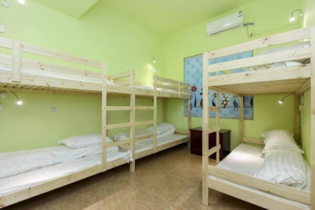 A room with bunk beds, a poster on the wall, and an air conditioning unit.