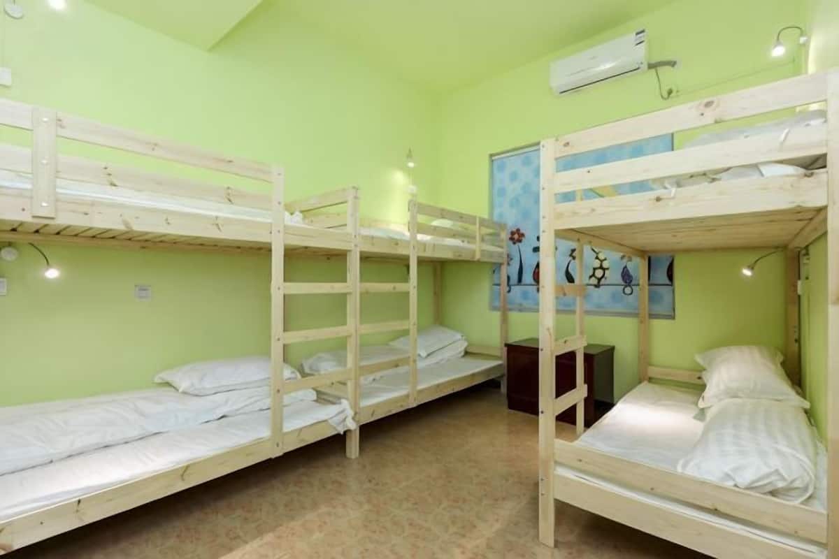 A room with bunk beds, a poster on the wall, and an air conditioning unit.
