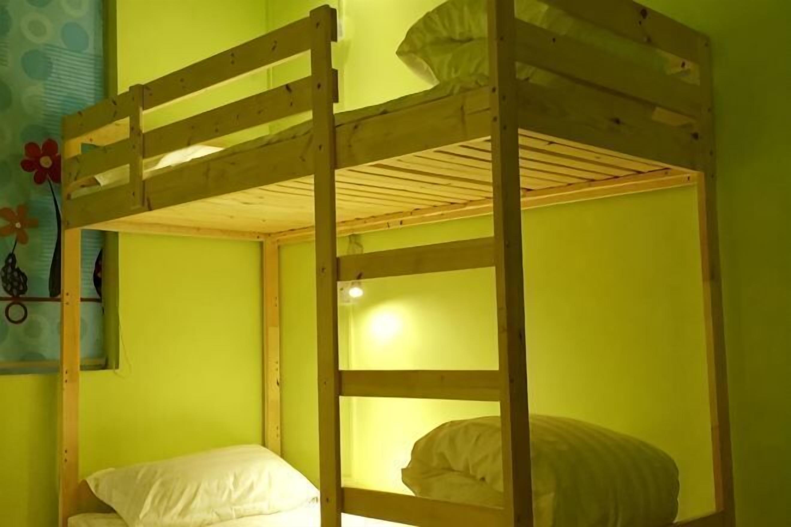 A bunk bed in a room with green walls and a floral decoration.