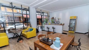 A modern interior with a wooden dining table, yellow chairs, and a kitchen area visible through large windows. - Jiahe Homestay (Emeishan Tourism Passenger Transport Center Baoguosi Station) (Emeishan City)