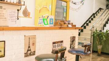 A bar area with stools, a yellow sign, and a staircase.