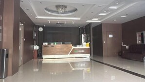 A reception desk with a modern design, a chandelier, and a clean, reflective floor. - Jiang Zhi Yuan Inn (Changbai County)