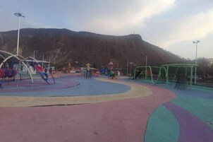 Un parque infantil con diversas estructuras de juego y una montaña al fondo.