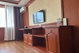 A room with a TV mounted on the wall, wooden furniture, and a window with curtains.