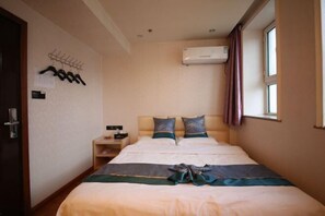 A hotel room with a bed, a nightstand, a wall-mounted air conditioner, and a window with curtains. - Jiang Zhi Yuan Inn (Changbai County)