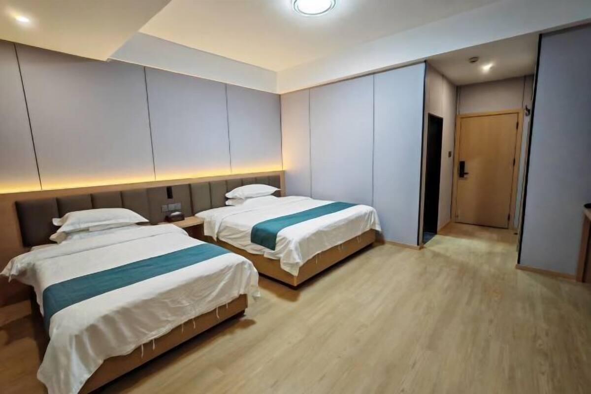 A hotel room with two beds, a wardrobe, and a door leading to another room.