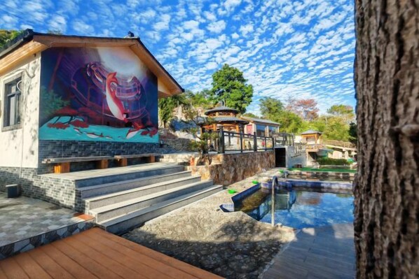 A building with a mural, steps leading to a pool, and a wooden deck.