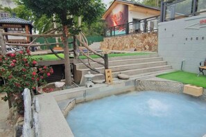 A hot spring area with steps leading to a pool, surrounded by greenery and a stone wall. - Ketianxia Hot Spring Resort (Longyan)