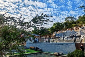 Piscina com muro de pedra e deck de madeira.