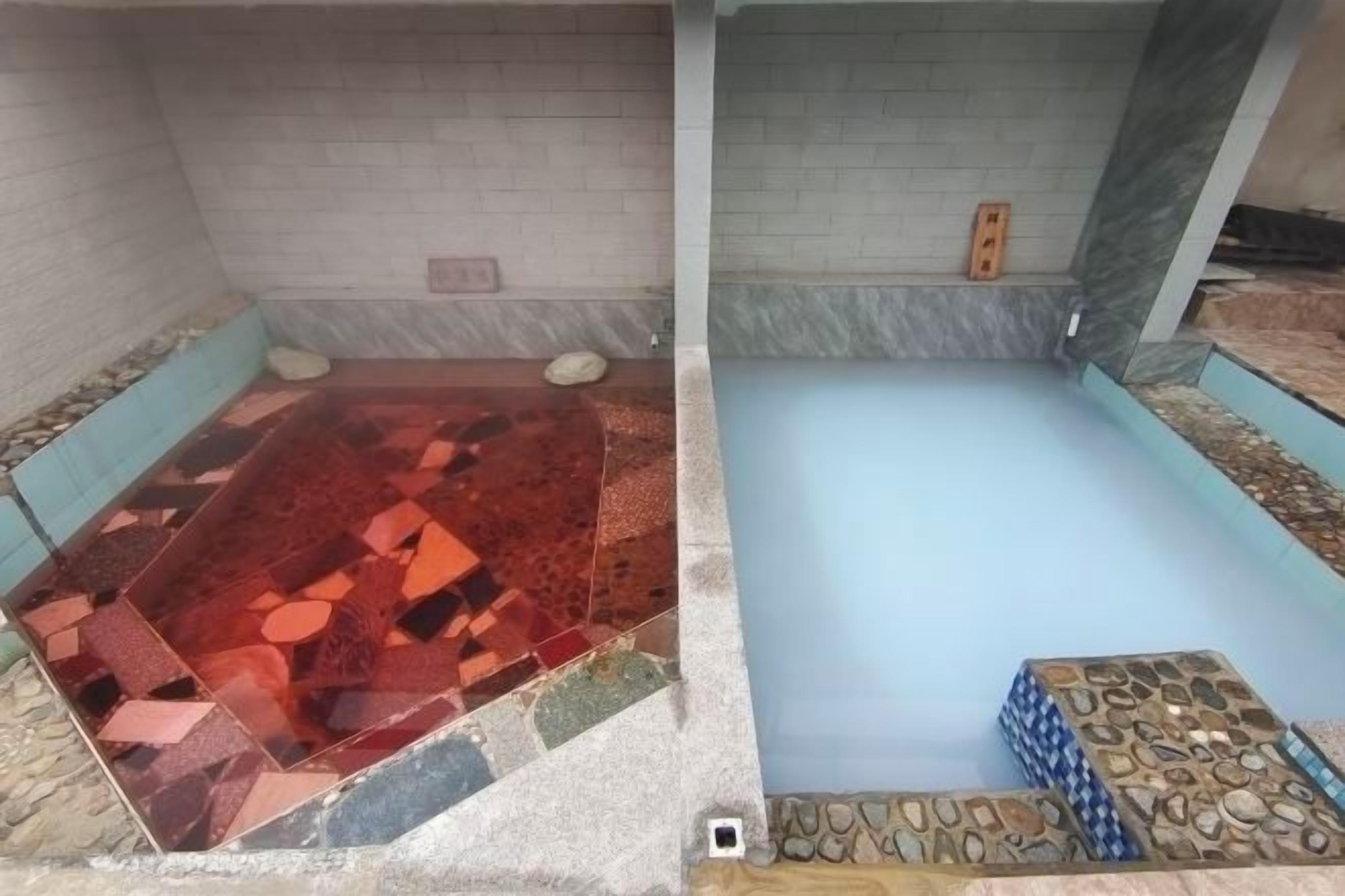 A spa area with a tiled floor, a blue pool, and a stone border.