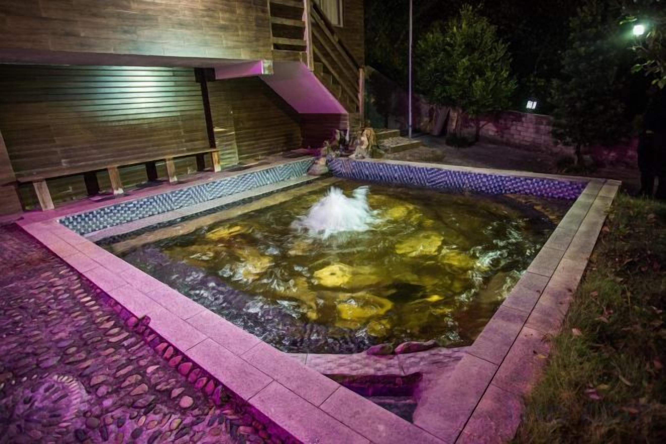 Een jacuzzi met betegelde rand en een houten terras eromheen.