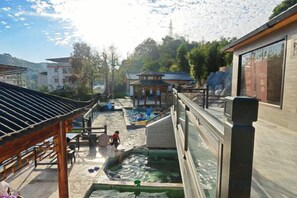 A traditional Japanese onsen with multiple hot spring baths, wooden walkways, and a view of the surrounding village. - Ketianxia Hot Spring Resort (Longyan)