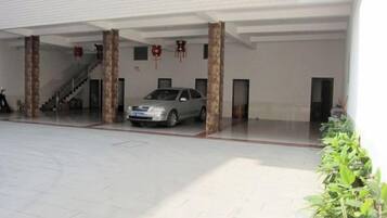 Un área de estacionamiento techada con un coche, una escalera y una puerta.