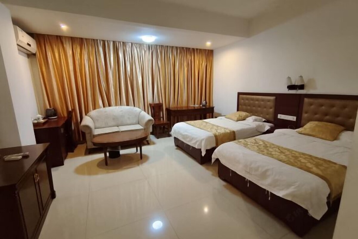 Una habitación de hotel con dos camas, un sofá, una mesita y una silla.
