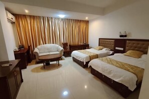 Una habitación de hotel con dos camas, un sofá, una mesita y una silla.