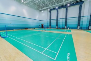 An indoor badminton court with a wooden floor and blue markings. - Petroleum Science & Technology Communication Center (Beijing)