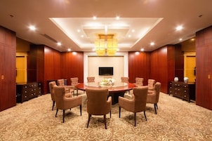 A conference room with a round table, multiple chairs, a flat-screen TV, and a decorative centerpiece.