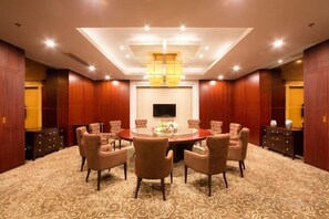 Un salón de conferencias con una mesa redonda, varias sillas, un televisor de pantalla plana y una decoración central.