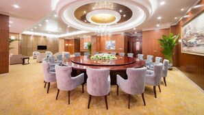 Un salón de conferencias con una mesa redonda, sillas alrededor y una araña.
