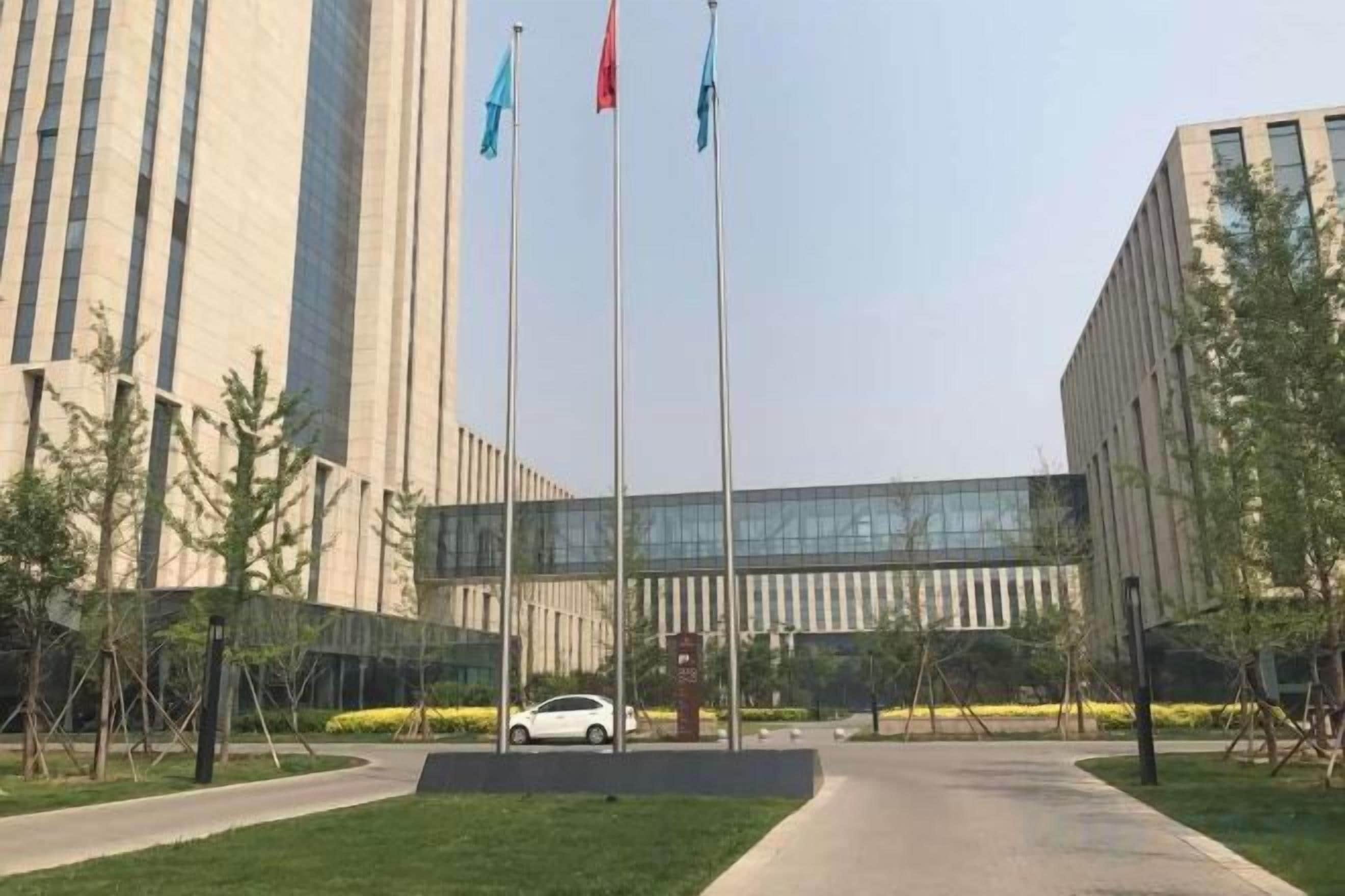 A building with a modern design, a paved entrance, and a flagpole with flags.