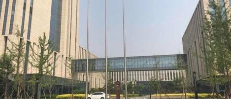A building with a modern design, a paved entrance, and a flagpole with flags.