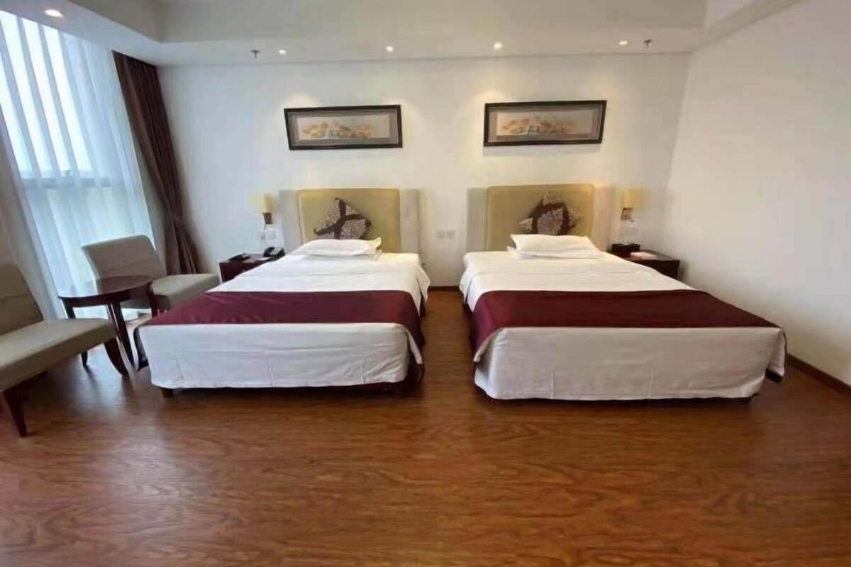 Ett hotellrum med två sängar, ett skrivbord och en stol.