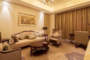 A living room with a sofa, armchairs, a coffee table, and a painting on the wall. - Tantai Lake Hotel (Suzhou)