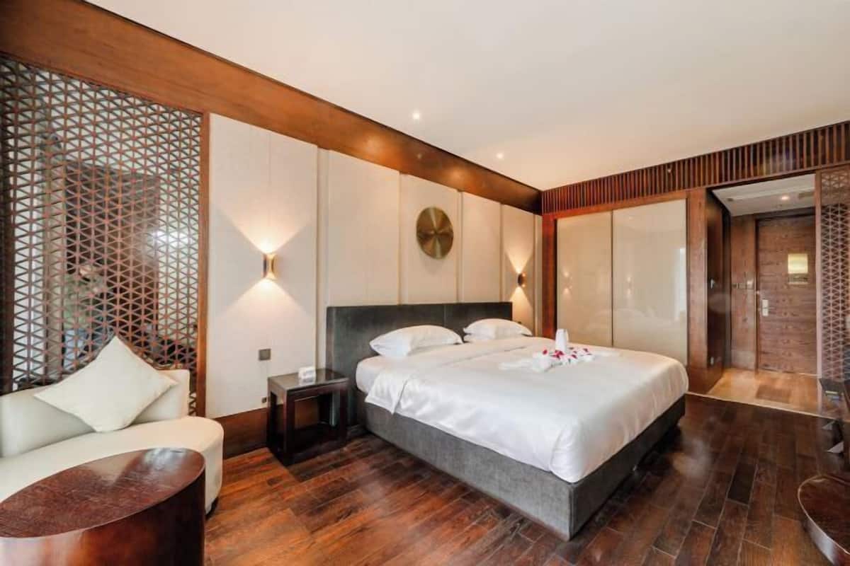 Une chambre d’hôtel moderne avec un grand lit, un canapé, une petite table et un panneau décoratif au mur.