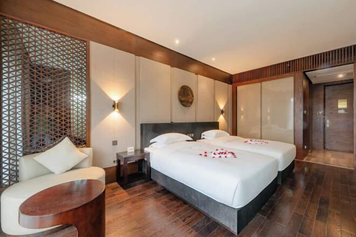 Une chambre d’hôtel avec deux lits, un canapé, un plancher en bois et un panneau décoratif au mur.