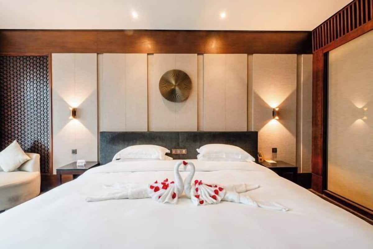 Une chambre d’hôtel avec un grand lit, deux tables de chevet, une tête de lit et des appliques murales.