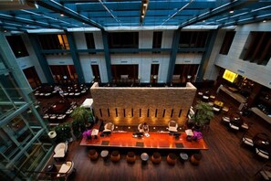 Un vestíbulo amplio con una zona de bar central, arreglos de asientos y un alto techo con tragaluces.