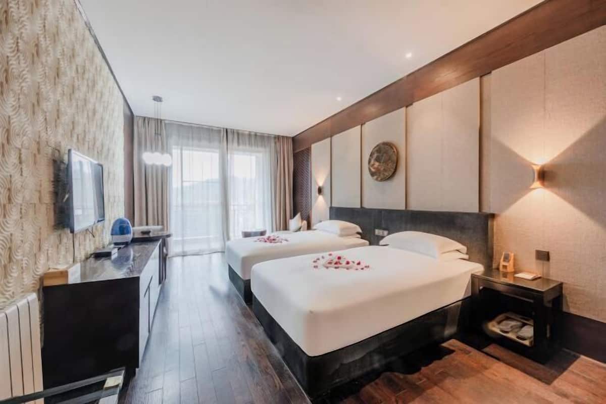 Une chambre d’hôtel avec deux lits, un bureau, une télévision et une grande fenêtre.